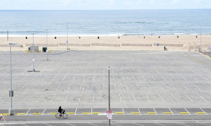 A cyclist rides past an empty parking lot at Santa Monica beach in California -- more than a third of the US population are under stay-at-home orders