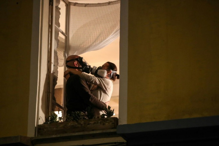 A couple in masks embrace at their window during the daily 8 o'clock applause in support of medical workers in the French Riviera city of Nice