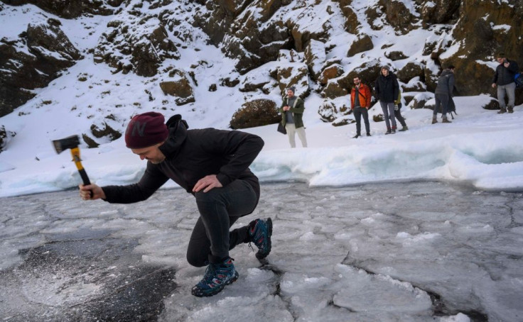 Andri Einarsson, co-instructor on the cold bathing seminar, cuts a hole through the sheet of ice covering the lake