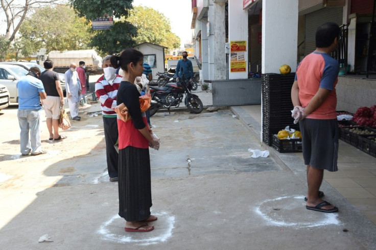 People mantain social distancing as they queue outside a grocery store in Faridabad