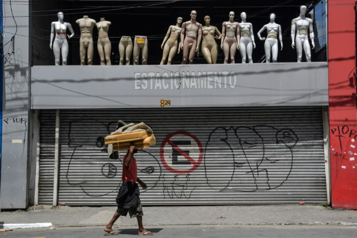 A homeless walks past a closed parking lot and mannequins in downtown Sao Paulo, Brazil, after the city government decreed the closure of shops and stores as a precautionary measure against the spread of the novel coronavirus COVID-19, on March 24, 2020