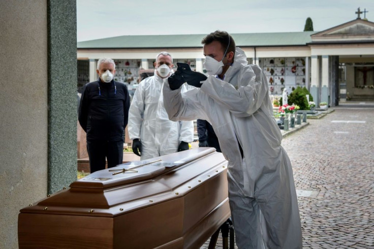 A pallbearer takes a picture of a coffin for the relatives of someone who has died, at a cemetery in the Italian province of Bergamo