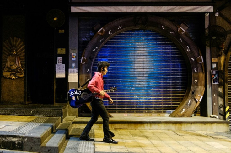 Kwok Lam-sang, who has been performing covers of Elvis Presley songs under the name of "Melvis" since 1992, walks with his guitar past closed bars in the usually busy drinking area of Lan Kwai Fong in Hong Kong