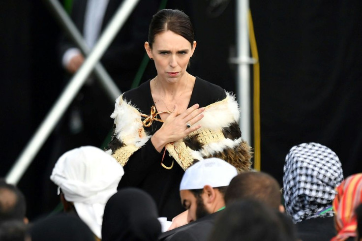 Prime Minister of New Zealand Jacinda Ardern places her hand over her heart as she walks past a family who lost members in the mosque attacks of 2019