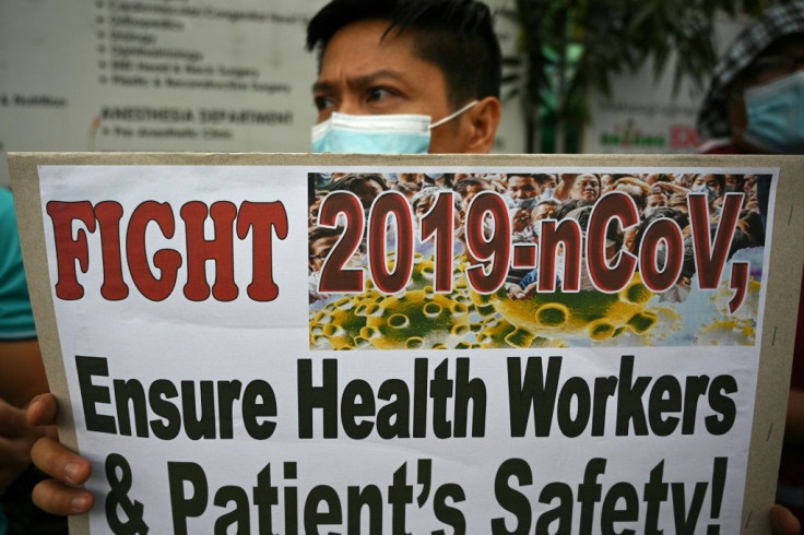A health worker wearing a face mask holds a placard during a protest in front of a government hospital in Manila