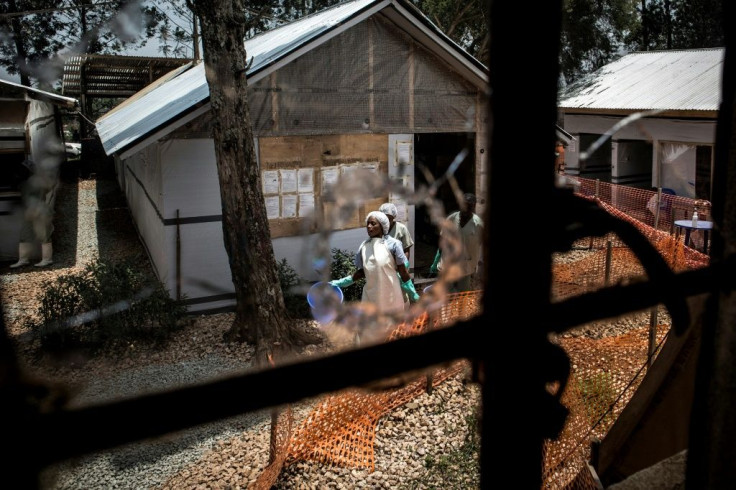 Dangerous times: Health workers are pictured through a bullet-holed window at an Ebola treatment centre in the eastern DR Congo city of Butembo. The facility was attacked twice in early 2019 by armed men hostile to its work