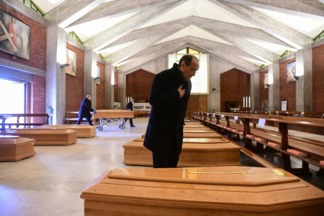 A priest says a quiet prayer over the rows of coffins at the warehouse on Bergamo's outskirts