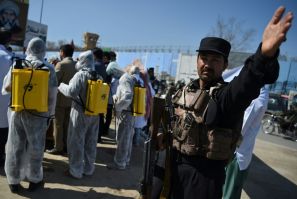 An Afghan policeman gestures as volunteers wearing a hazmat suits and a facemasks gather before the start of a preventive campaign against the spread of the COVID-19 coronavirus, in Kabul on March 18, 2020