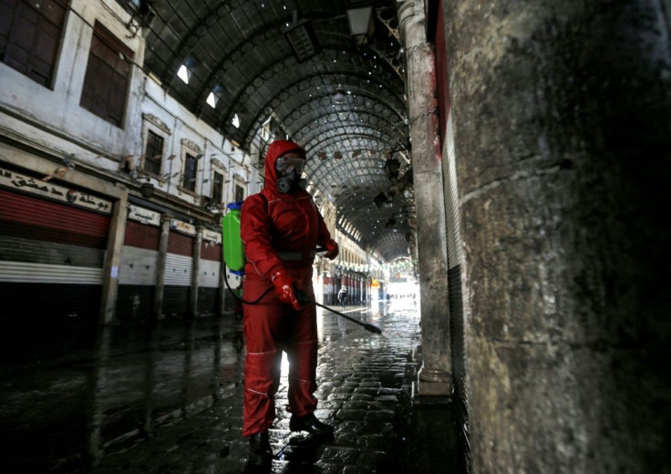 A Red Crescent member sprays disinfectant along an alley of the historic Hamidiya souk (market) in the old city of Syria's capital Damascus as part of efforts against the coronavirus pandemic