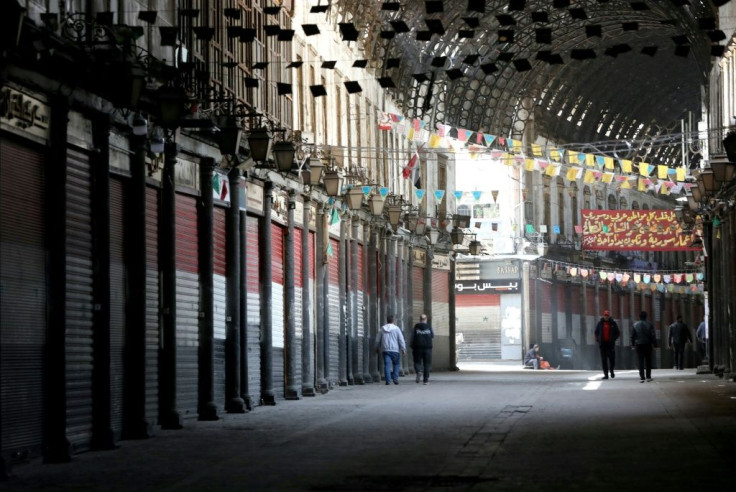 People walk through the shuttered century-old covered bazaar of Hamidiya in Syria's capital Damascus