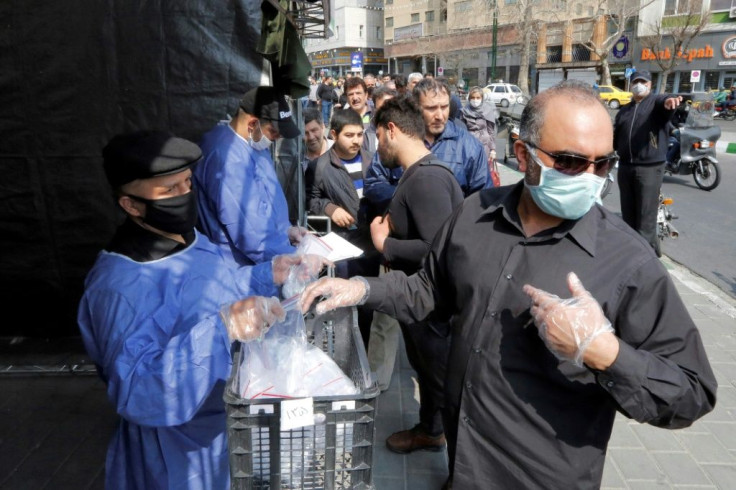 Tehran residents wait outside a metro station to receive packages to protect against the COVID-19 coronavirus disease provided by the Basij, a militia loyal to the Islamic Republic's leadership