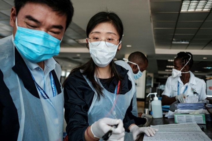 Chinese embassy officials help screen incoming passengers for the new coronavirus as they arrive at Entebbe Airport in Uganda on March 3, 2020