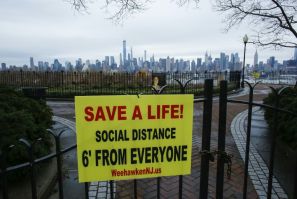 A sign encouraging social distancing to stop the spread of coronavirus is displayed in a park in New Jersey, with the New York city skyline in the background