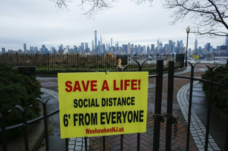 A sign encouraging social distancing to stop the spread of coronavirus is displayed in a park in New Jersey, with the New York city skyline in the background