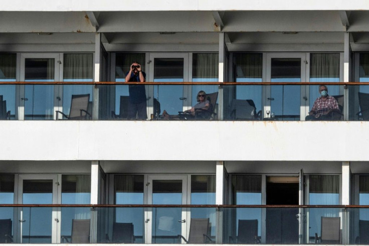 A passenger uses binoculars as another wears a face mask onboard Holland America's cruise ship Zaandam as it entered the Panama bay on March 27, 2020