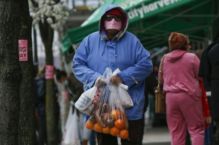 A woman carries bags with food from the City Harvest food bank in Harlem, New York City