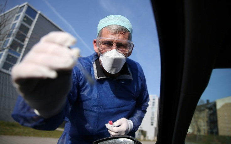 German doctor Michael Grosse takes a sample from a car driver at a drive-through testing point for the coronavirus in Halle, eastern Germany