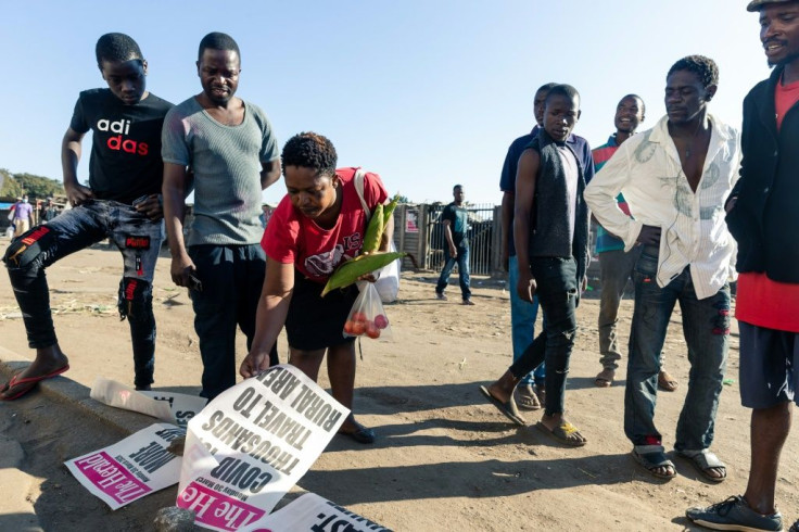 People look at the newspaper headlines in Mbare, a surbub of Harare, where all food markets were closed on Monday as part of a three-week lockdown