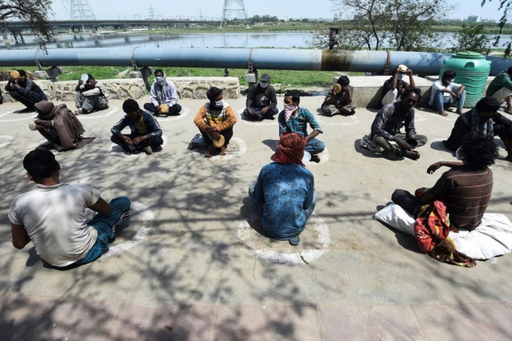 Homeless Indians sit in "isolation circles" outside a shelter while waiting for food in New Delhi