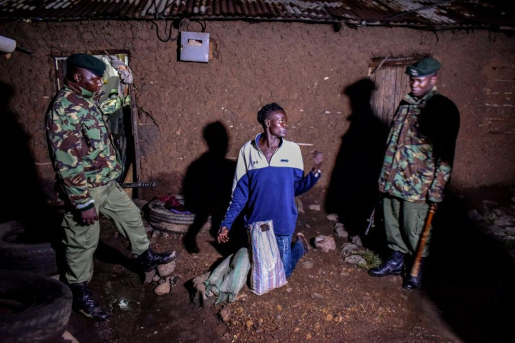 Security officers in Kisumu, western Kenya, arrest a man selling alcohol door to door during the curfew