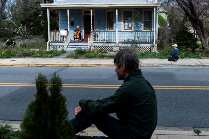 People watch cellist Jodi Beder perform a daily concert on her front porch in Mount Rainier, Maryland near Washington, DC