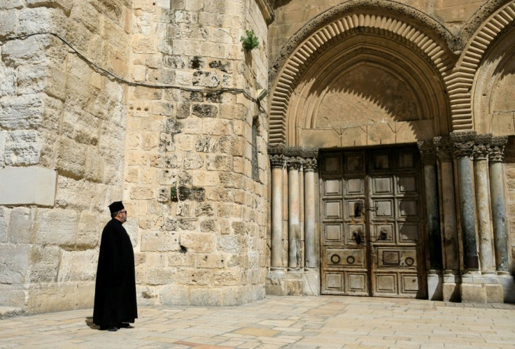 A Greek Orthodox priest gazes at the closed door of the Church of the Holy Sepulchre in the Old City of Jerusalem following the closure of the city for non-residents