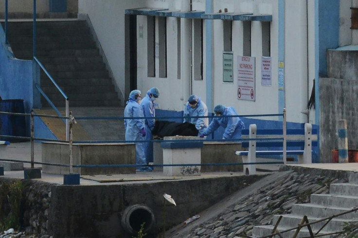 Staff wearing protective gear prepare to cremate a body at the North Bengal Medical College and Hospital in India