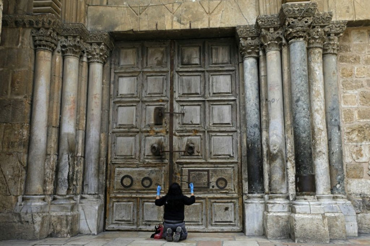 A woman prays in front of the doors of Church of the Holy Sepulchre in the Old City of Jerusalem following its closure due to the coronavirus