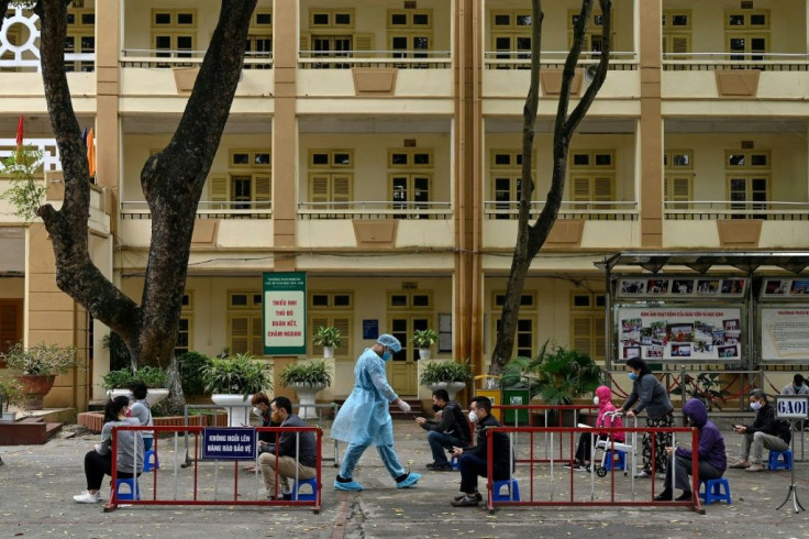 Residents wearing face masks practise social distancing as they wait to be tested at a makeshift rapid testing centre in Hanoi, Vietnam