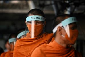 Buddhist monks wear face shields as they collect alms in Bangkok, Thailand