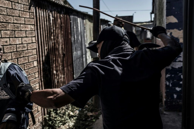 A policeman in Cape Town's Cape Flats forces a man who was hiding between buildings to go home