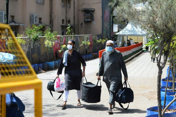 Muslims who attended a religious gathering in Nizamuddin, New Delhi, walk to a bus taking them to quarantine after a Coronavirus outbreak