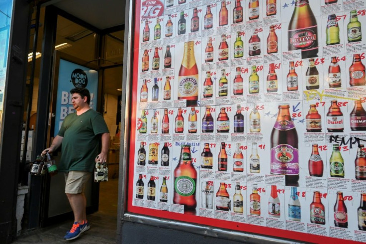 A man leaves a "bottle shop" displaying a sign showing dozens of beers for sale in Melbourne after major alcohol retailers in the country agreed to enforce new rules limiting individual purchase