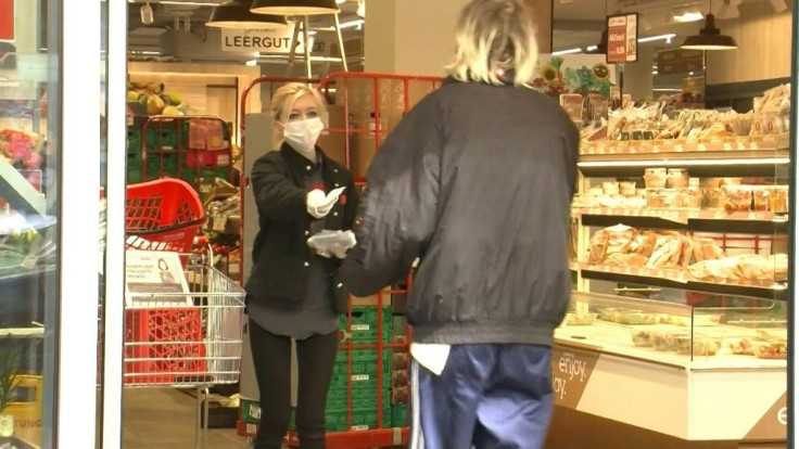 Supermarket employees hand out masks to customers as they enter, as Austria implements new rules compelling people to cover their faces in public places to slow the spread of coronavirus