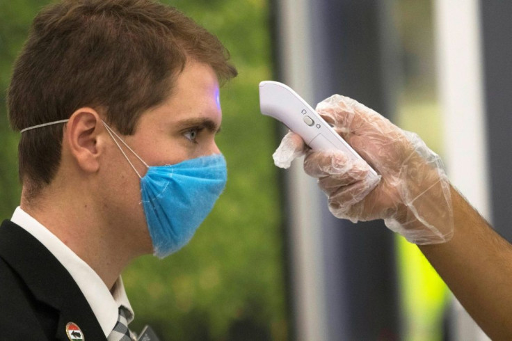 A worker checks the temperature of a passenger at the still-open Benito Juarez International airport, in Mexico City, on April 1, 2020