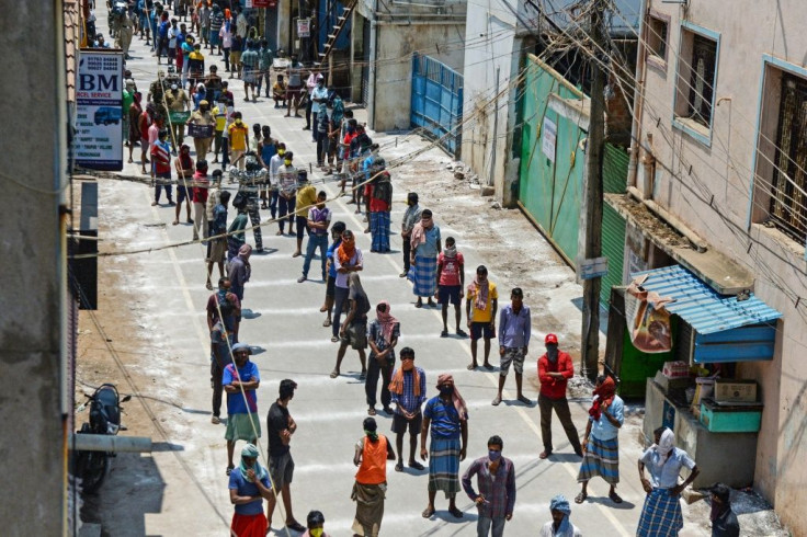 Migrant workers wait on marked areas on the ground to maintain social distancing as they queue to receive food packets in Chennai, India