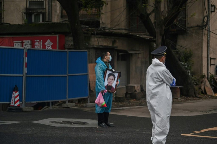 A man wearing a face mask and carrying a portrait of a loved one stands outside the Biandanshan cemetery in Wuhan