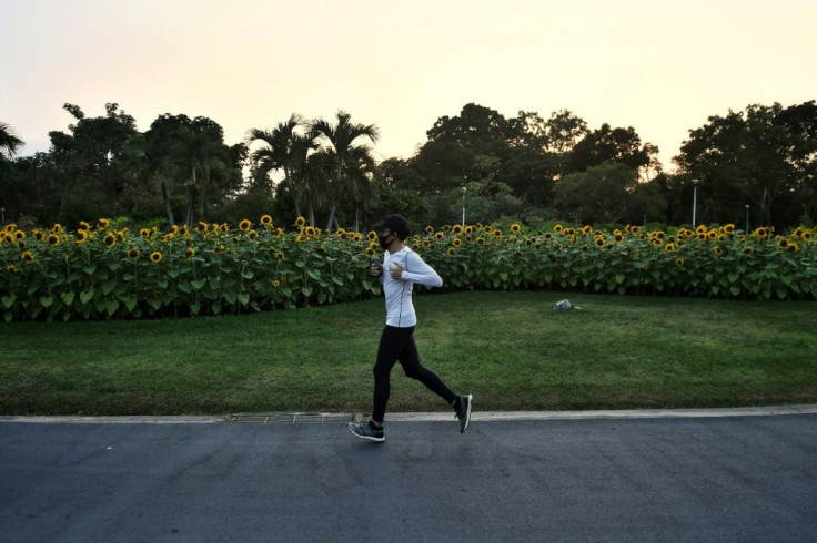A jogger runs past a row of sunflowers in Jatuchak Park before authorities shut shut down more public places in the Thai capital