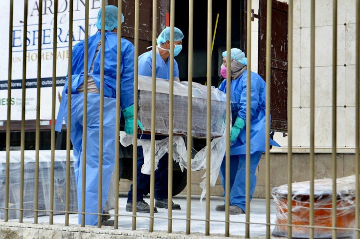 Employees wearing protective gear carry a coffin wrapped in plastic at a cemetery in Guayaquil on April 1