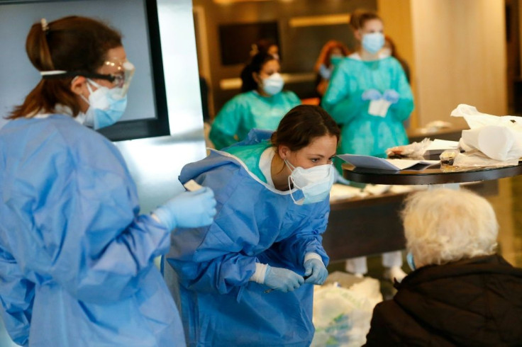 Healthcare workers attend to a COVID-19 patient upon her arrival at the Hotel Melia Barcelona Sarria in Barcelona, after the hotel was transformed into a medical centre