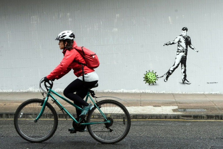 A cyclist passes coronavirus-inspired graffiti in Glasgow on April 4, 2020, as life in Britain continues during the nationwide lockdown