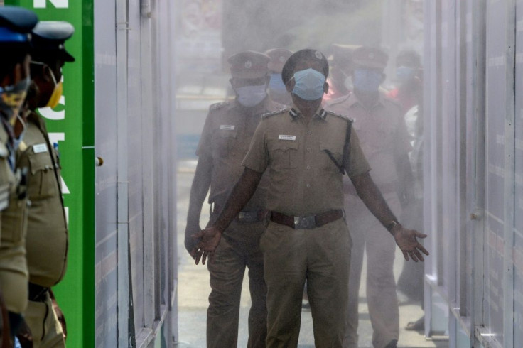 Indian police walk through a disinfection tunnel during a government-imposed nationwide lockdown