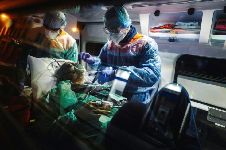 A French first aid worker from the Protection Civile Paris Seine holds an oxygen mask over the mouth and nose of a male patient suspected of being infected with COVID-19 a he lies in an ambulance