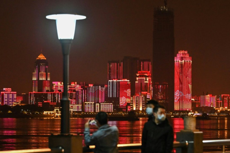 People wearing facemasks walk near the Yangtze River in Wuhan, epicentre of the coronavirus, which reported no new deaths from the disease for the first time since January