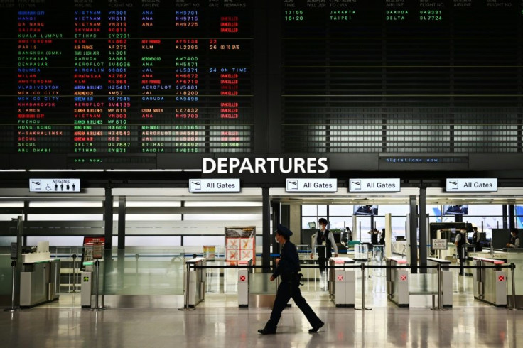 A security guard walks past a signboard showing cancelled flights at the international departures area of Narita International Airport in Narita, Japan -- Prime Minister Shinzo Abe said the country's hospitals face a "critical situation"