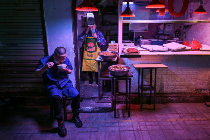 A man eats lunch next to a market stall in Wuhan