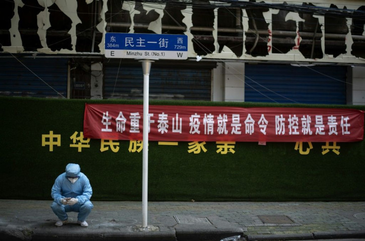 A man wearing a hazmat suit uses his phone in Wuhan