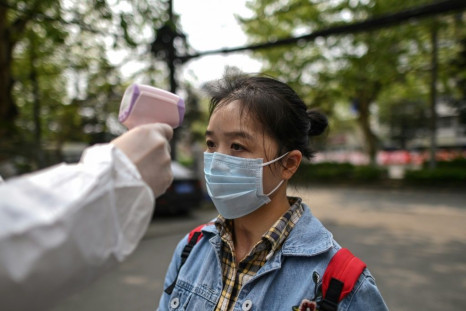 A man wearing a protective suit checks a woman's temperature in Wuhan, a city of 11 million people