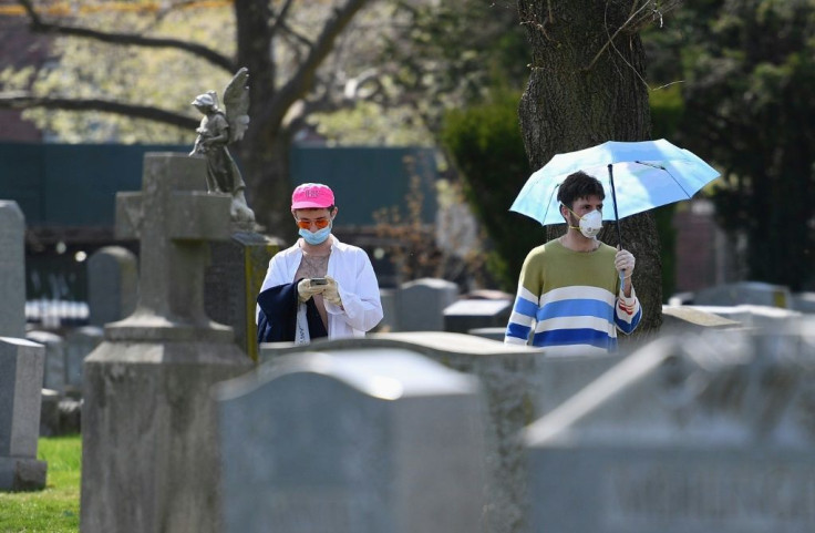 People wearing face masks walk through a cemetery in Brooklyn