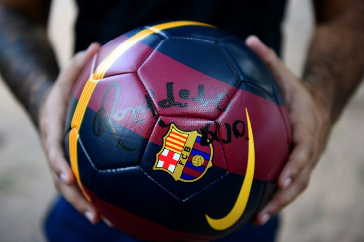 A football fan shows a ball signed by Ronaldinho outside the National Police headquarters in Asuncion on March 12, 2020, where the football great and his brother Roberto Assis had been held